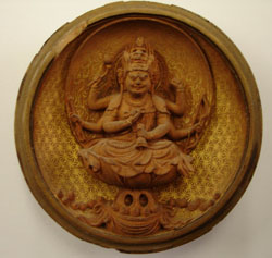 Theosophical Society - Bodhisattva that Colonel Henry S. Olcott received from an influential family during his travels through China in 1890 (figure 8). (A Bodhisattva, in Mahayana Buddhism, is an individual who has vowed to postpone individual salvation in order to work on behalf of the liberation of all sentient beings.) Srimati Rukmini Devi, an Indian Theosophist celebrated for her efforts at reviving Indian classical dance, gave this piece of art to Joseph on October 2, 1978, so that it would be delivered to America to strengthen the links of East and West. Joseph writes that "the artisan who created it was well versed in Hindu symbolism, yet he melded it into a typically Chinese visage and trunk. The five circular coins on the cover represent the fourfold lower worlds of personality plus the one of the spirit represented by the bird...The landscape inside the cover represents...the planet earth. The figure sits on a lotus in space as represented by the starry background."